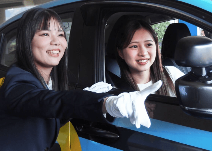 車の中から外を見て笑顔を見せる2人の教習生